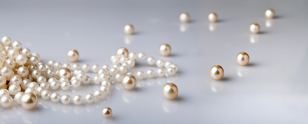 pearl beads and pearls with reflection on gray background Perlenschnur Familienerbe