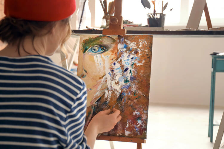 Female artist painting in workshop Die Idealisierung beenden